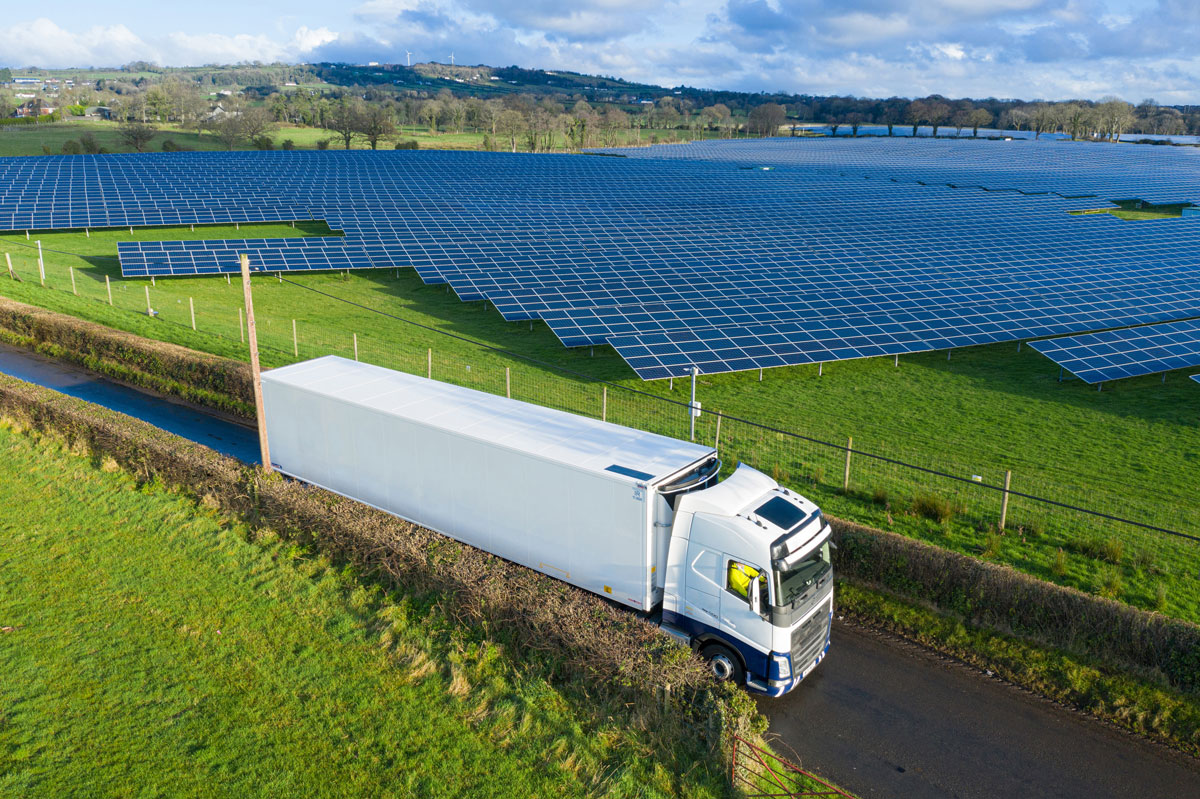 Refrigerated trailer with solar panel on the roof and a field of solar in the background Refrigerated trailer with solar panel on the roof and a field of solar in the background