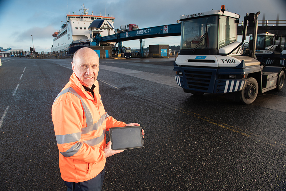 A Terberg tug in front of the P&O ferry in Larne and an engineer using a tablet to access Freeway Fleet Systems